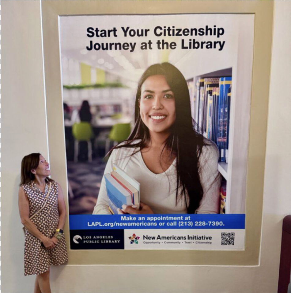 Dana C. Arnett at the Los Angeles Central Library beside New Americans Initiative campaign creative developed with the Los Angeles Public Library